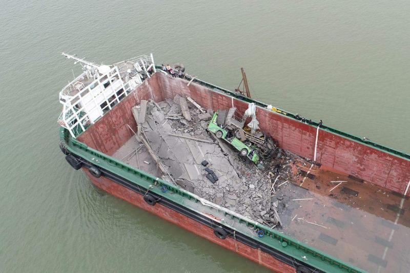 桥面共有四辆车和一辆电动摩托车从断裂处坠落,其中一辆空载中巴车、一辆货车和一辆电动摩托车坠落到集装箱船舱内,两辆小货车掉落水中。(新华社)