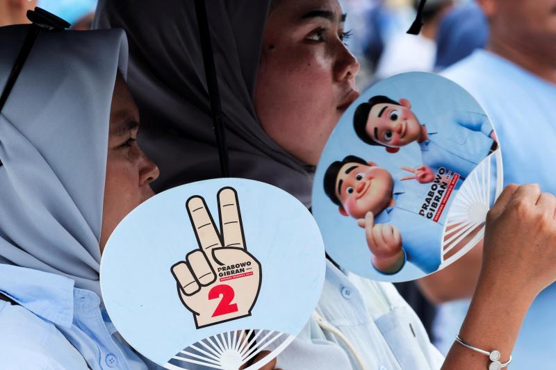 在印尼总统选举中领跑的普拉博沃在竞选中广泛使用AI技术。图为支持者手持印有普拉博沃和竞选搭档吉布兰卡通画像的扇子。(路透社)
