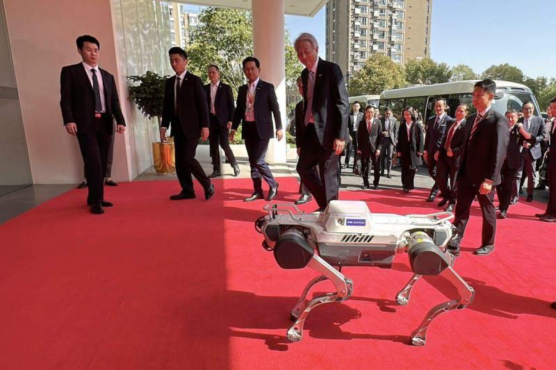 张志贤(左五)到访浙江中控技术股份有限公司时,公司自行研发的机器狗在门外迎接。(陈婧摄)