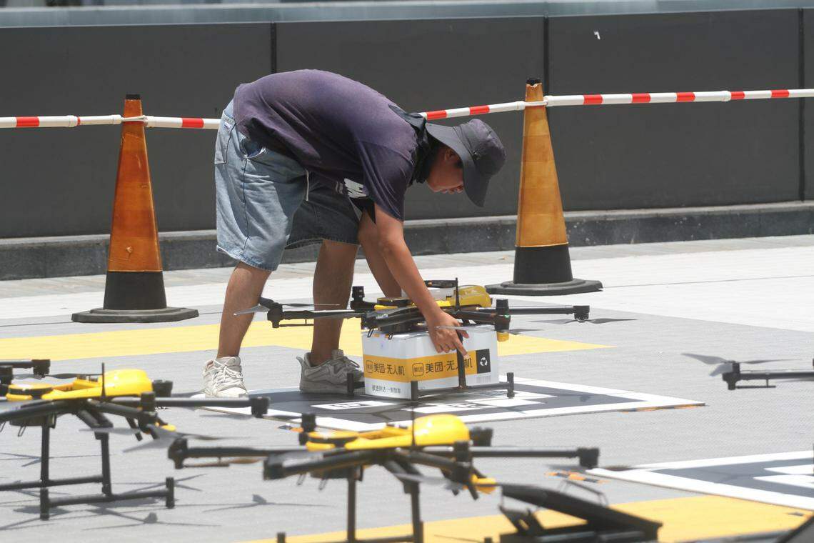 美团工作人员将外卖餐盒放置在无人机下,准备派送。(林煇智摄)