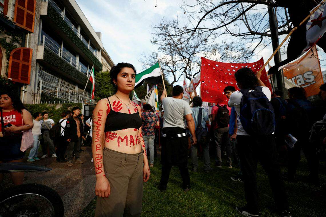 9月27日,一名抗议者在阿根廷参加阿米尼抗疫活动时,用红色颜料在身上画上代表“触摸”的手掌和抗议字眼。(路透社)