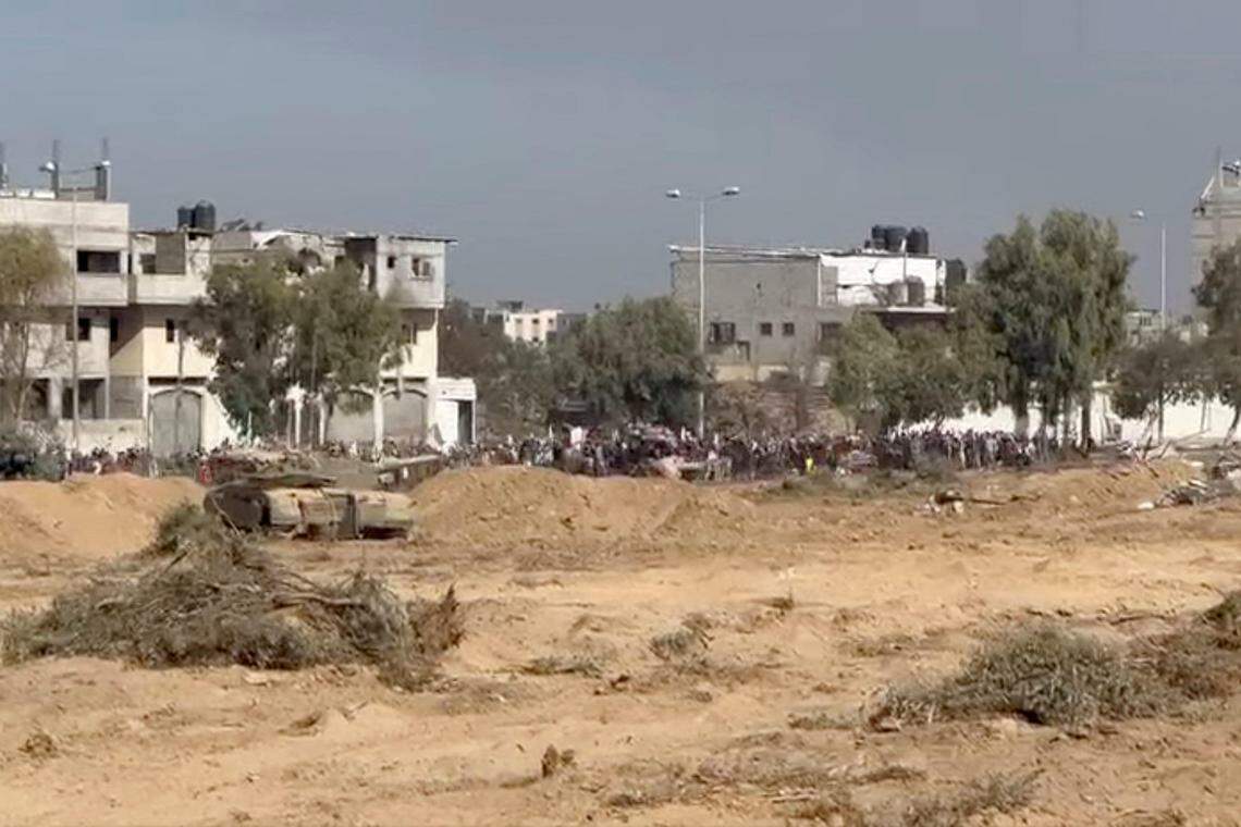 以色列军队11月7日发布照片,显示一群巴勒斯坦人举着白旗,经过以色列军队的坦克车,从加沙北部往南撤离。(路透社)