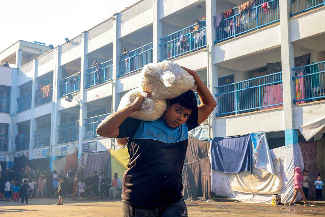 加沙地带的粮食目前仅从拉法(Rafah)运入。11月14日,在拉法一所由联合国难民救济处管理的学校里,一个男孩抬走他所配得的粮食。(法新社)