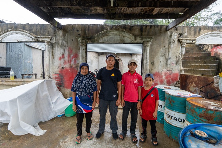 丹绒拉边村民卜再亚(左二)的家在冲突中被烧毁,他和家人至今仍住在残破的房子里。(特约邓德兴摄)