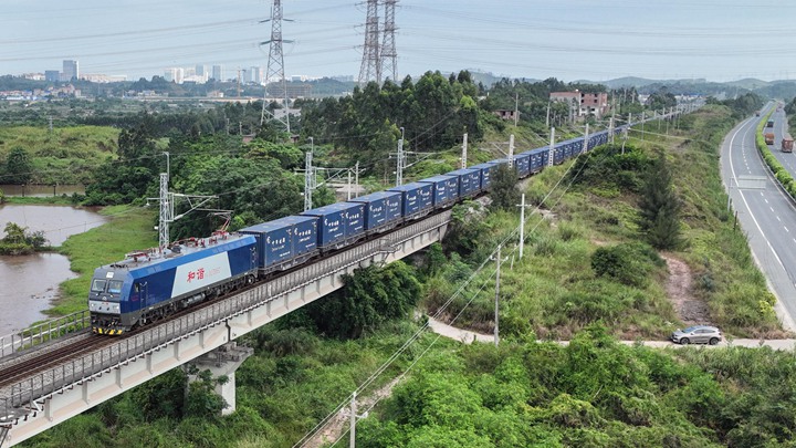 满载集装箱的货列,10月9日穿行在西部陆海新通道的铁路上。(新华社)