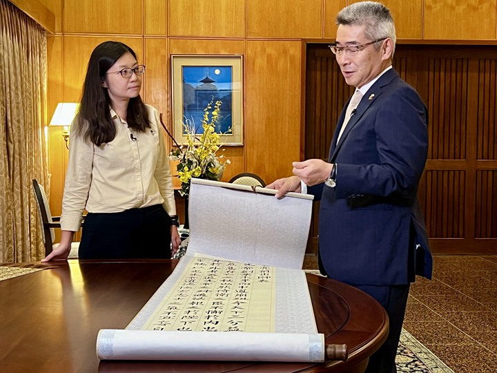 日本大使石川浩司(右)向《联合早报》视频编导许淑美展示他的书法作品,内容取自诸葛亮《出师表》首段,他表示内容“很令人感动”。(吴汉钧摄)