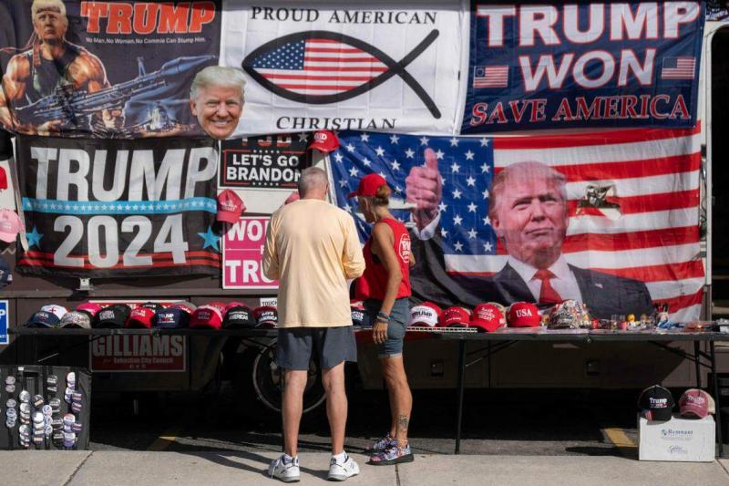 特朗普有许多“铁粉“,图为2023年11月8日,特朗普的支持者在佛罗里达州的一场竞选集会会场购买他的帽子、徽章等周边商品。(法新社)