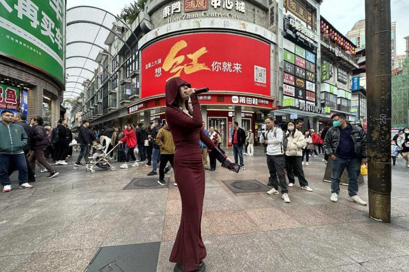 东门大型电子广告牌打出“想红你就来”,公开向更多网红发出邀请。一名网红在东门步行街十字路口直播唱歌。(林煇智摄)