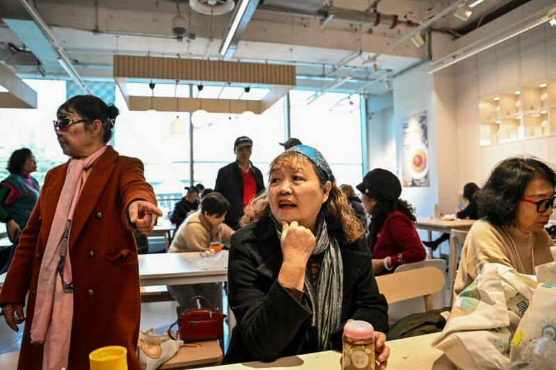 佩戴发带的退休医生徐怡珍(音译),去年12月5日在上海徐汇区宜家餐厅内与朋友聊天。(法新社)