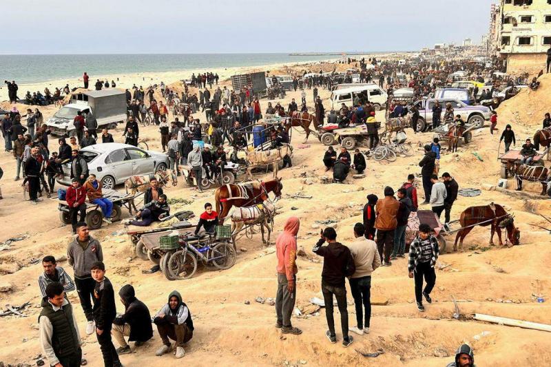 战斗持续,必需品短缺,许多巴勒斯坦人生活困难。大批巴勒斯坦人星期一(2月26日)聚集在加沙城的以色列检查站附近,等待装载面粉的卡车到来。(路透社)