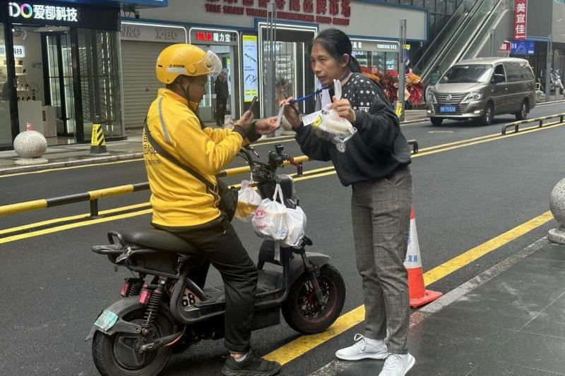 外卖骑手将外卖交给代送阿姨后,就可继续其他派送任务。(林煇智摄)