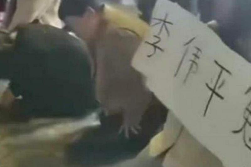 视频显示,网民上周涌到开封包公像前集体“申冤”,其中一名女子举着“李伟平冤”的牌子。(互联网)