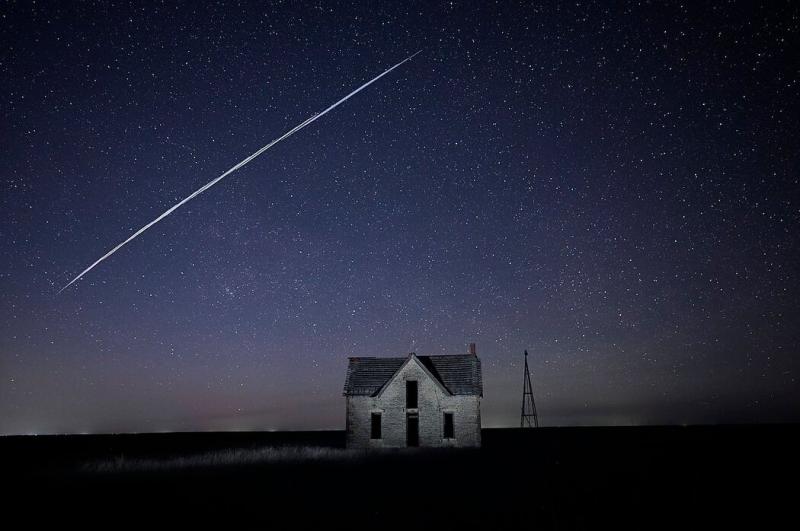 这张2021年拍摄的长时间曝光照片记录了SpaceX的一个星链卫星穿过堪萨斯州佛罗伦萨附近一栋古老石屋上空的景致。