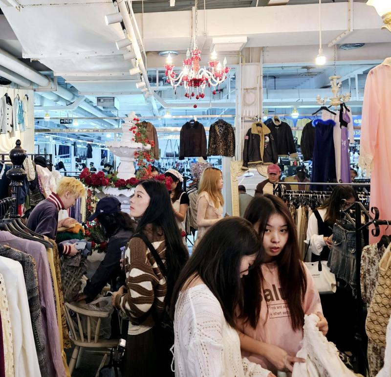 26岁的娄馨月半年前到董家溪开了一家二手服装店。图为周末下午到店里淘古着的年轻人。(王纬温摄)