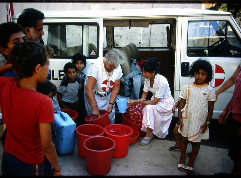1988年,洪瑞钗(右二)和巴勒斯坦人医药援助会的义工派发牛奶给西贝鲁特难民庇护所的儿童。(受访者提供)