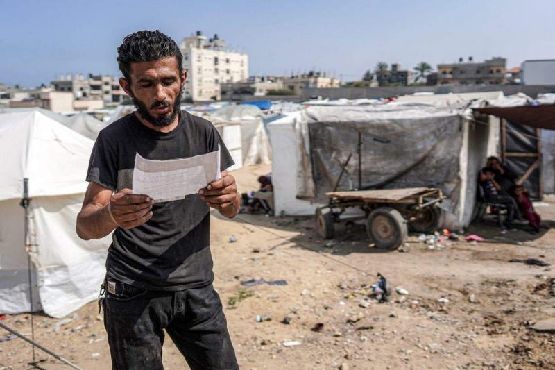 星期二在加沙地带中部城市代尔拜拉赫地(Deir el-Balah),巴勒斯坦民众接到以军投下的阿拉伯文传单。传单上说,加沙干河(Wadi Gaza)以北是“危险战区”,警告人们尽快远离。 (法新社)