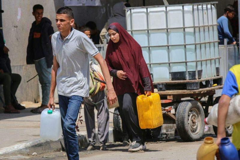 拉法目前出现高温天气,在那里避难的巴勒斯坦民众5月3日提着容器到取水处拿水。(彭博社)