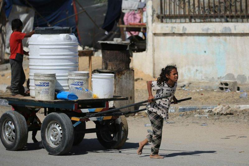 加沙地带在以军持续多月的猛烈轰炸下,人道危机不断恶化,断粮且严重缺水。图为加沙南部城市汗尤尼斯,小女孩吃力地拉车运水。(法新社)