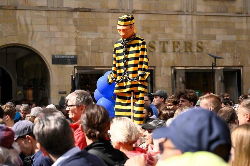 德国民众5月28日在西部城市明斯特(Muenster)市政厅前集会,他们举着身穿囚服的普京肖像,抗议法俄进行核领域的合作。(法新社)