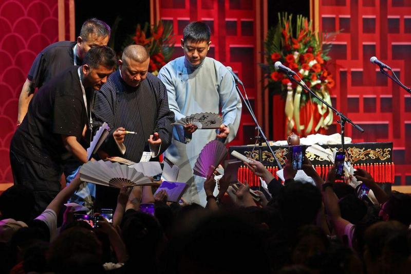 近四小时表演结束后,大批热情“钢丝”拿着扇子、书籍等各种物品涌到台前,争相索取郭德纲签名。(陈渊庄摄)