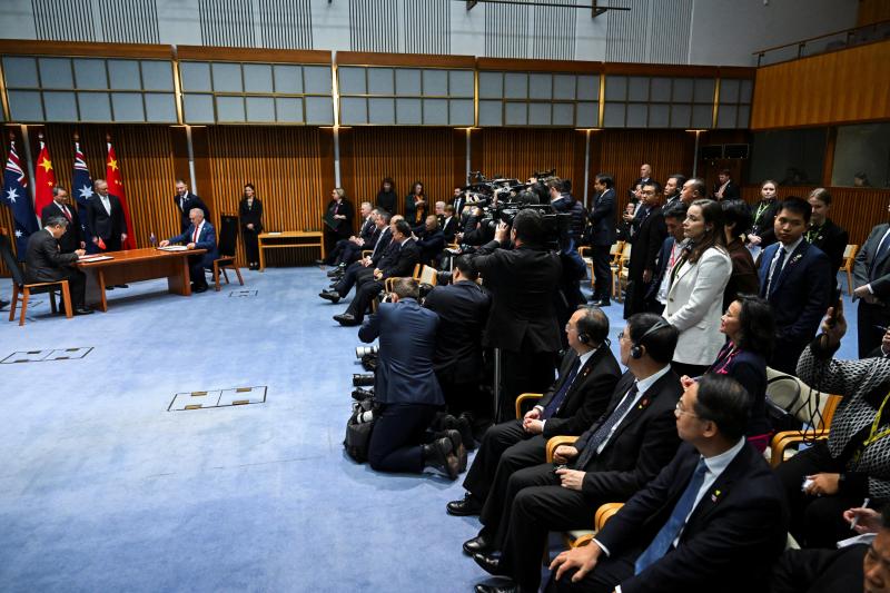 成蕾(坐在图右后排者)6月17日以澳洲天空新闻记者的身份现身中澳合作文件签署仪式现场媒体区,一度疑遭两名中国官员阻挡,引来澳洲官员(白衣站立者)干预。(路透社)