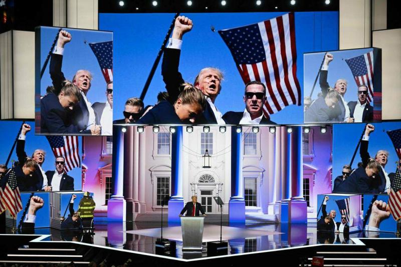 特朗普星期四在台上演讲时,背后大屏幕上出现他遭枪击后挥拳的照片。(法新社)