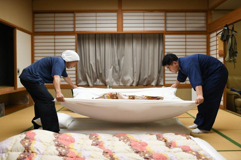 来自尼泊尔的古隆·尼桑(右)在日本传统温泉旅馆里铺布团。