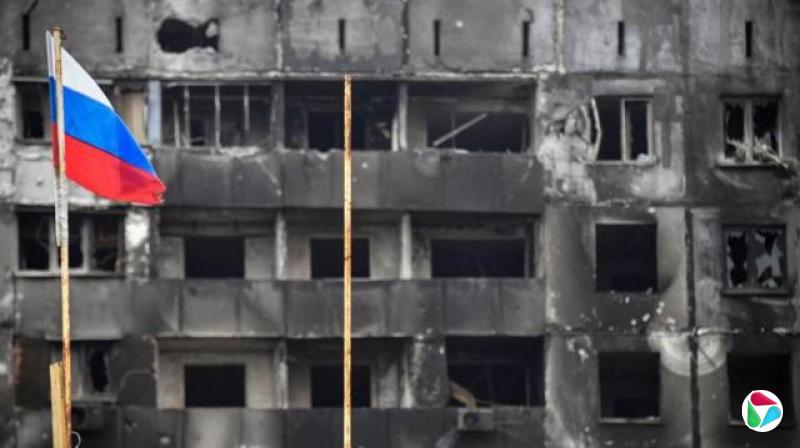 A Russian national flag flies by destroyed buildings in Mariupol on April 12, 2022,