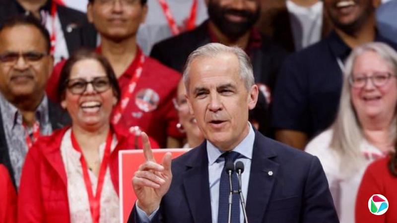 加拿大总理马克·卡尼(Mark Carney)在选举之夜于自由党总部发表演说。他的身后是一群支持者。他举起手,脸上带着微笑。