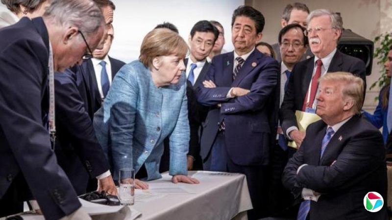 这张由德国政府于2018年6月9日发布的新闻照片显示,在加拿大沙勒瓦举行的G7峰会第二天,法国总统伊曼纽尔?马克宏(左三,部分被遮挡)、德国总理安格拉?梅克尔(左中)与日本首相安倍晋三(右中)正在与美国总统唐纳?特朗普(右,坐着)交谈