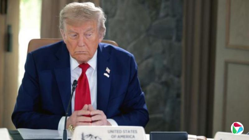 特朗普在亚伯达举行的G7会议上,坐在桌前,双手交握,望向右侧