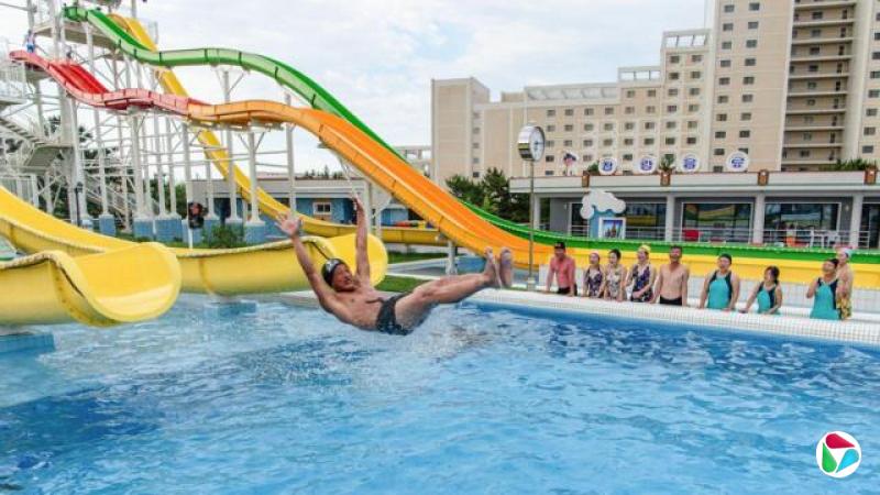 国内游客在“元山葛麻海岸旅游区”(Wonsan Kalma Coastal Tourist Area)内的“明沙十里水上乐园”(Myongsasimni Water Park),观看一名男子使用滑梯滑入游泳池,地点位于朝鲜江原道元山市。