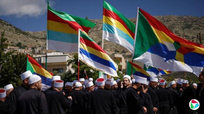 德鲁兹男子高举旗帜,头戴白帽,身穿黑袍