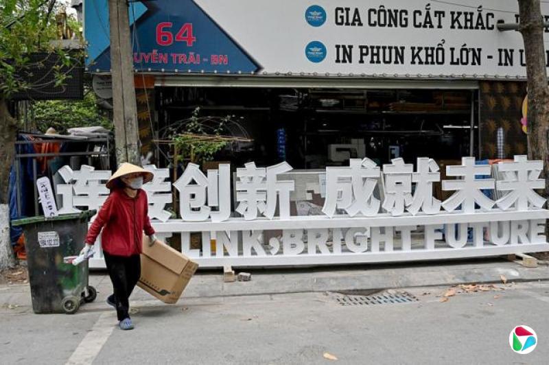 2024年4月10日的照片显示,一名废品收集者走过北宁省一块中文招牌前。在越南的许多中国企业,尤其是那些直接向美国出口的企业