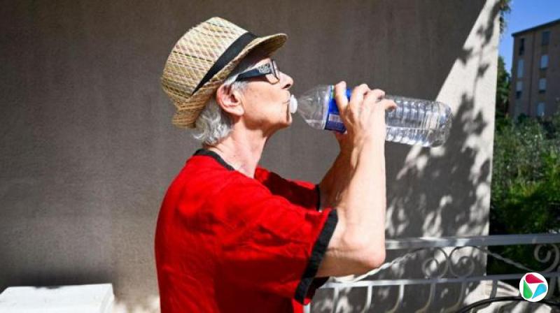 在法国耶尔,一名妇女在炎热的天气里喝水。