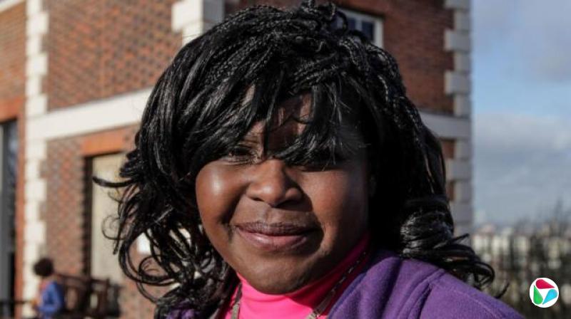 玛姬·阿德林-波科克博士身穿粉红色高领衫和紫色毛衣,直视镜头