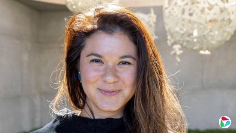 一名长发女子直视镜头,面带微笑。