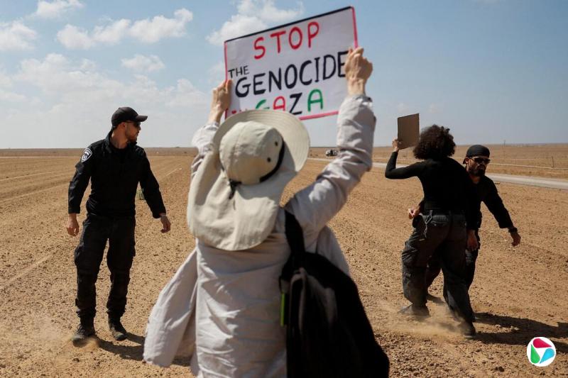 9月19日,从以色列一侧拍摄的照片显示,以色列警察在以色列和加沙地带边境阻止民众参加抗议活动,示威者举着的牌子写道“停止在加沙的种族灭绝行动”。(路透社)