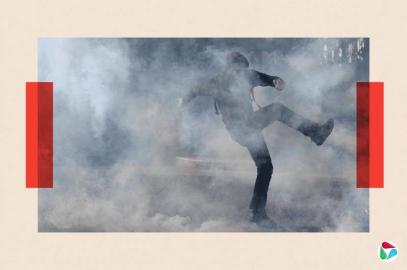 一名抗议者在与法国警方的冲突中冒着催泪瓦斯奔跑。