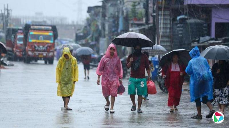 人们身着彩色雨衣,打着雨伞行走在大雨中。