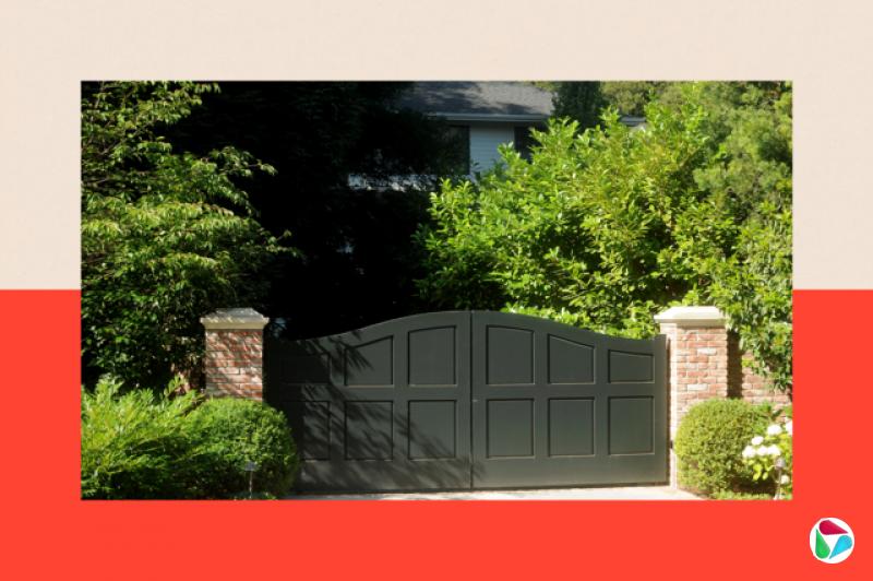 一道大型铁门与绿色灌木,背景中隐约可见一栋笼罩在阴影中的房屋。