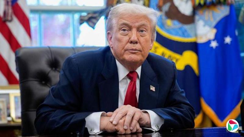 唐纳德?特朗普坐在椭圆形办公室里,双手交叉放置。