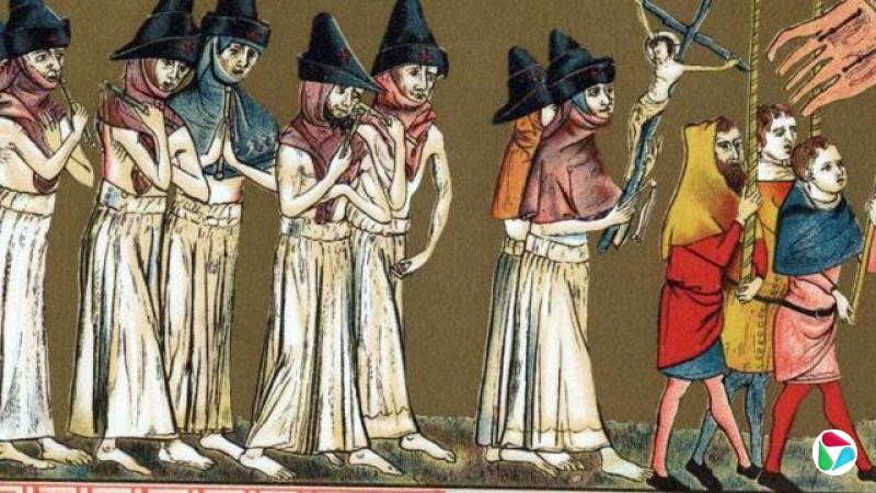 八名身穿白袍、戴着尖顶帽的人赤脚行走,在游行队伍中跟随着三名身着彩色服装的男子。这些男子手持旗帜。